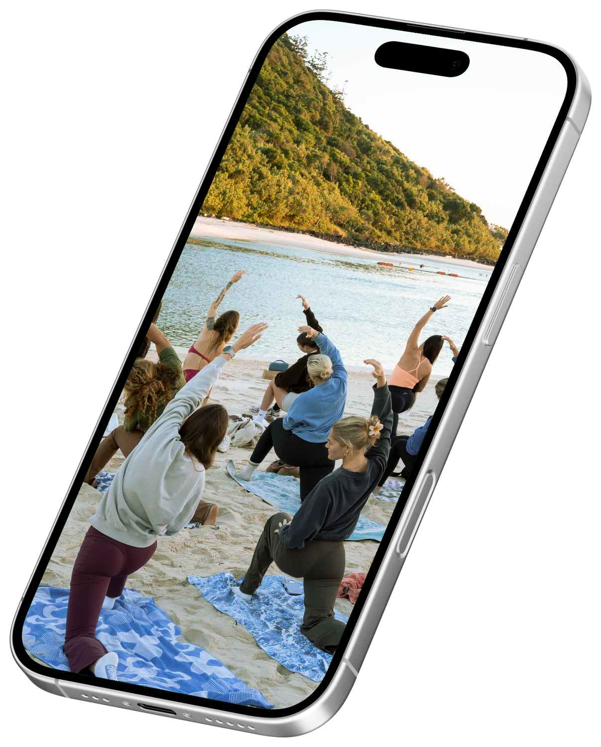 A Mikki’s Mobility class in warrior pose on the sand, shown on an angled iPhone.